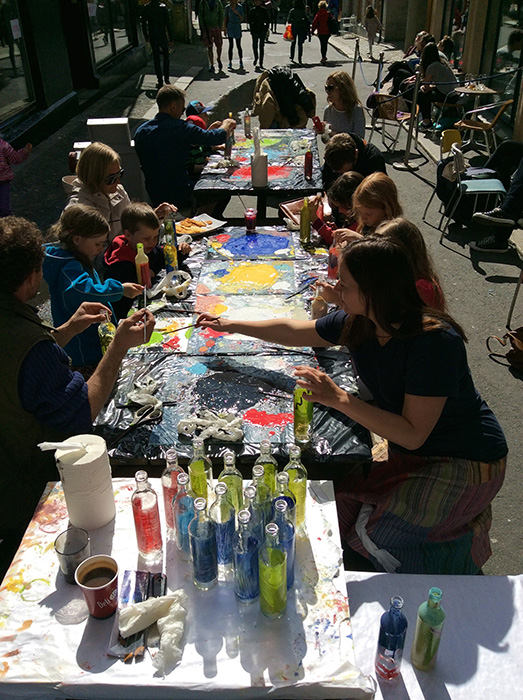 Barn og unge dekorerer de resirkulerte flaskene, uvitende om at malepaletten deres skal være med i utstillingen 